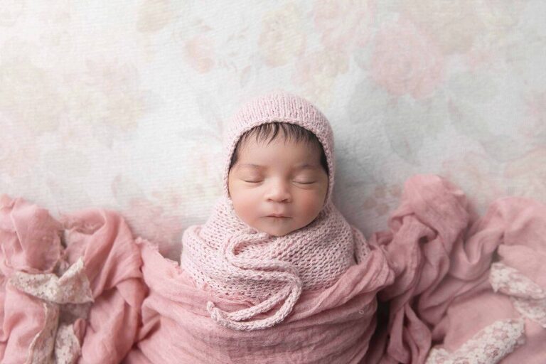 Newborn baby girl with a pink and floral set up with bonnet