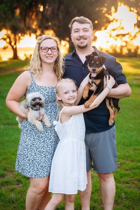 Family posing with 2 puppy dogs at Whitehall plantation in Beaufort SC