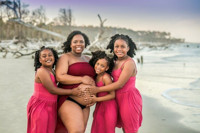 maternity portrait of mother with her 3 daughters on the beach