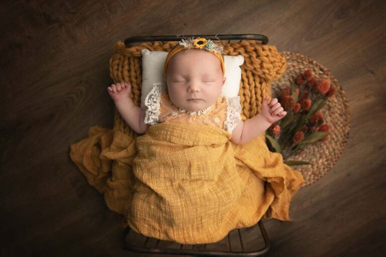 newborn girl in mustard yellow set up on a bed