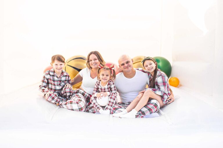 Family session in a white bounce house with over sized holiday ornaments for Christmas