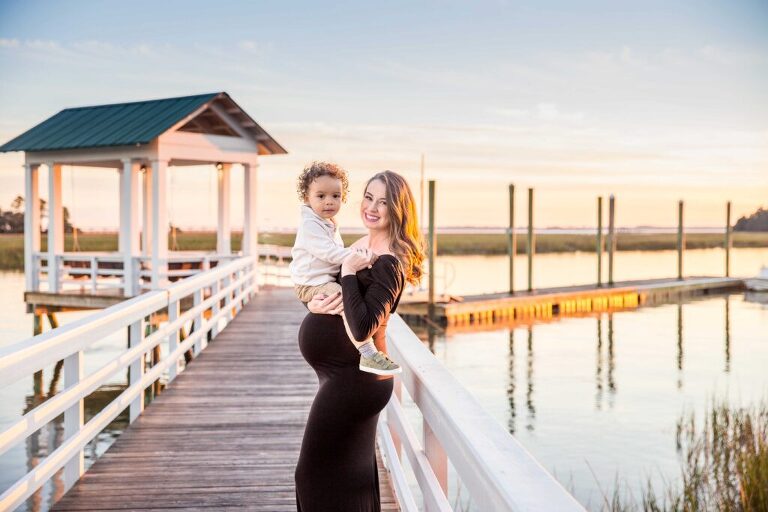 pregnant mother holding her toddler during her pictures on a dock in Bluffton sc