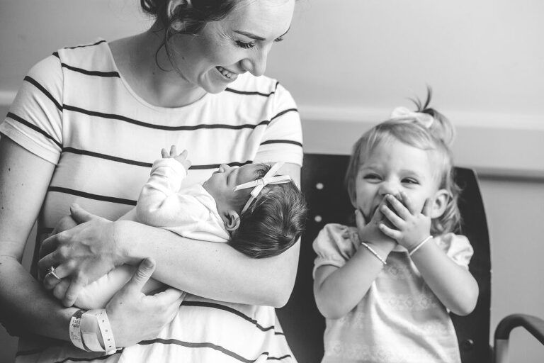 Little girl giggling at her new sibling during our fresh48 session at a beaufort area hospital 